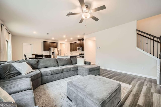 living area with a ceiling fan, stairway, dark wood-style floors, and baseboards