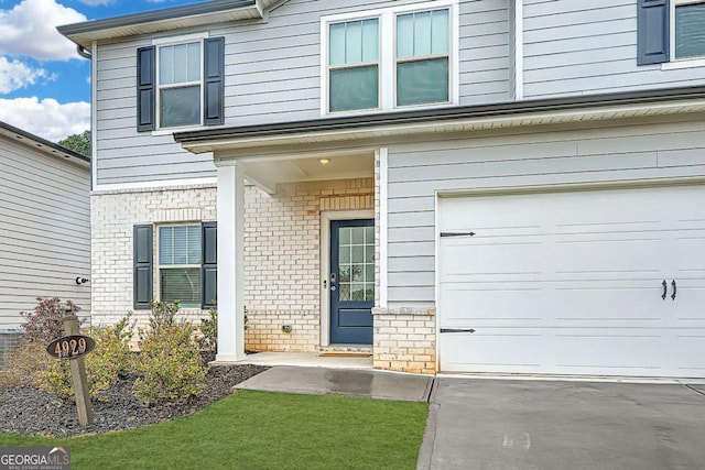 view of exterior entry featuring an attached garage and brick siding