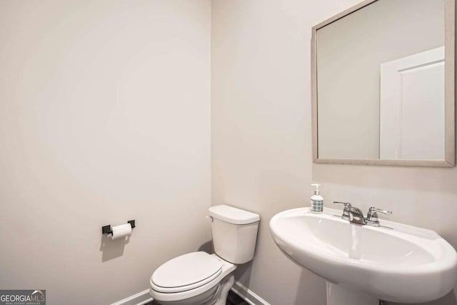 bathroom featuring toilet, baseboards, and a sink