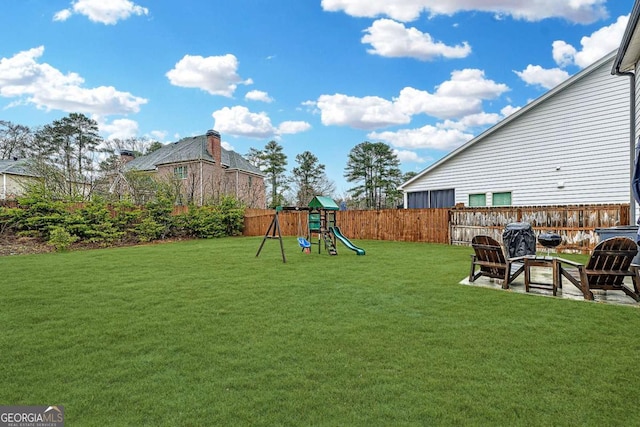 view of yard featuring a patio area, a playground, a fire pit, and a fenced backyard