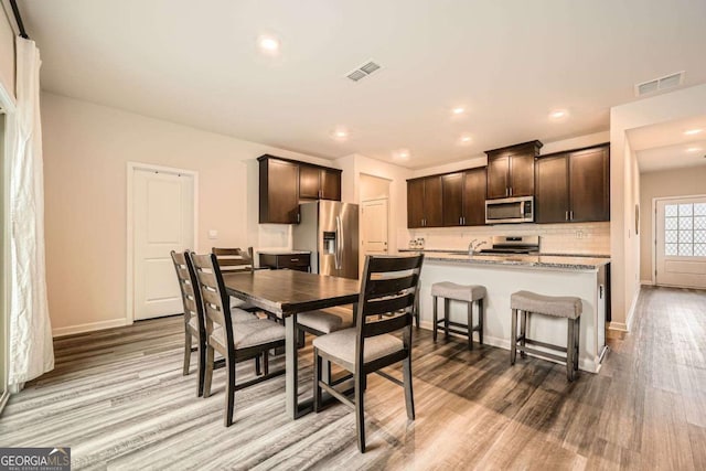 dining area with wood finished floors, visible vents, and baseboards