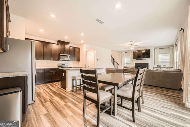 dining area featuring a ceiling fan, visible vents, recessed lighting, a fireplace, and light wood-style floors