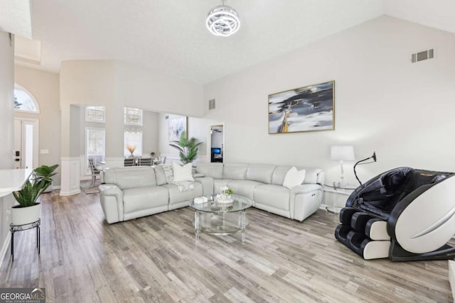 living room with lofted ceiling, wood finished floors, and visible vents