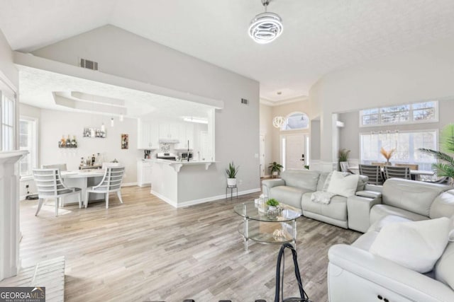 living room featuring visible vents, light wood-style flooring, high vaulted ceiling, and baseboards