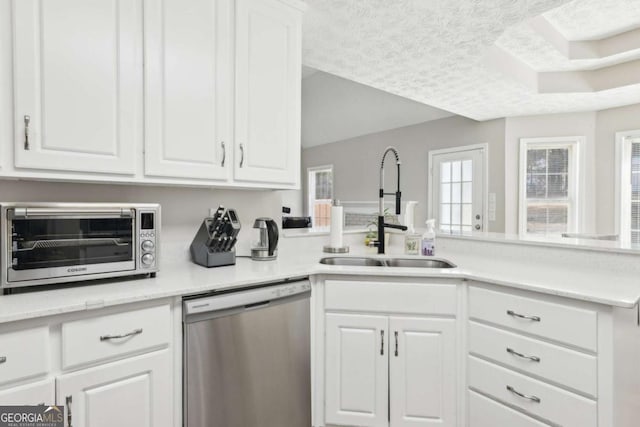 kitchen with dishwasher, a textured ceiling, white cabinets, and a sink