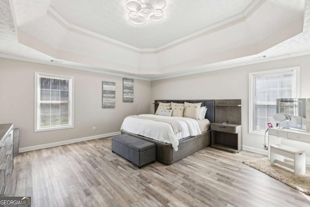 bedroom featuring ornamental molding, a raised ceiling, baseboards, and wood finished floors