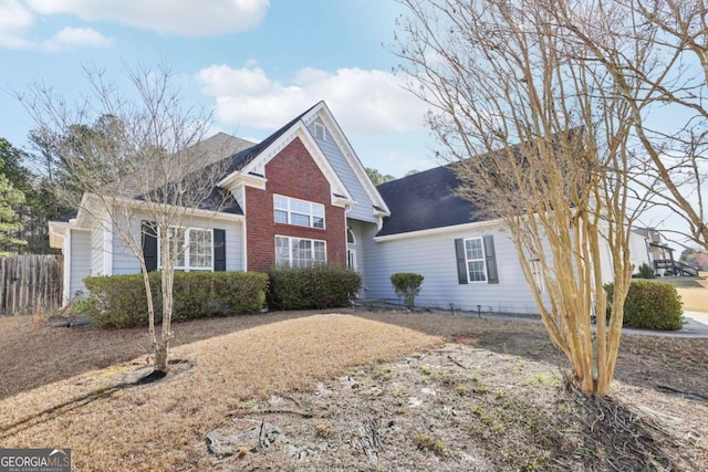 traditional home with brick siding, roof with shingles, and fence