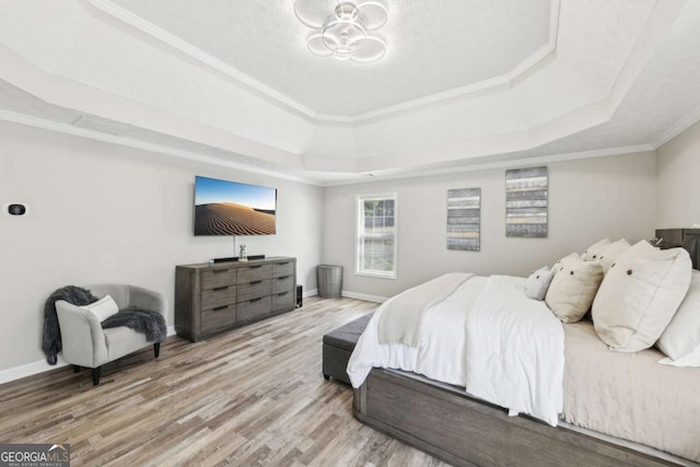 bedroom with a chandelier, baseboards, a tray ceiling, and wood finished floors