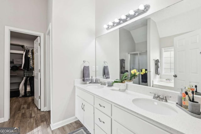 bathroom featuring a garden tub, a stall shower, a sink, wood finished floors, and a spacious closet