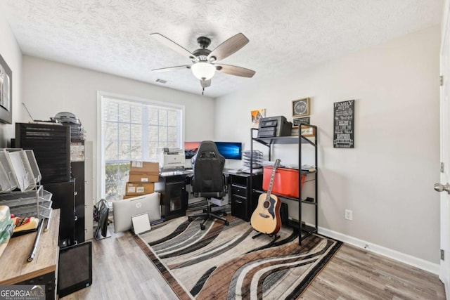 office space with visible vents, a textured ceiling, a ceiling fan, and wood finished floors