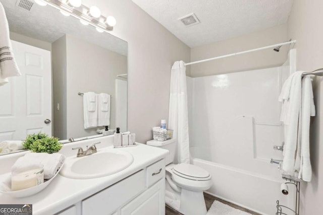 bathroom with vanity, visible vents, shower / bath combo, a textured ceiling, and toilet