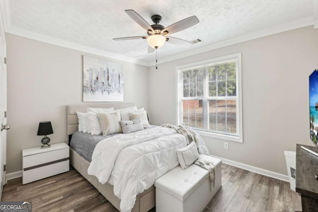 bedroom featuring visible vents, ornamental molding, and wood finished floors