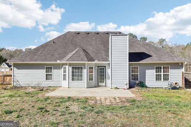 back of house with a patio, fence, a yard, a shingled roof, and a chimney