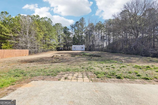 view of yard with an outbuilding, a storage shed, and fence