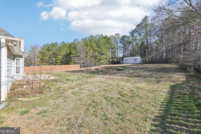 view of yard featuring an outbuilding, a storage shed, and fence