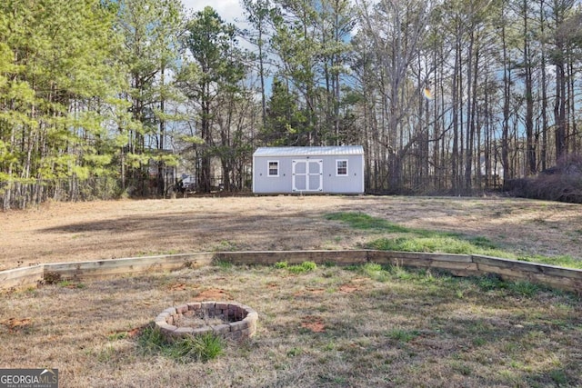 view of yard featuring an outdoor structure, a storage unit, a fire pit, and fence