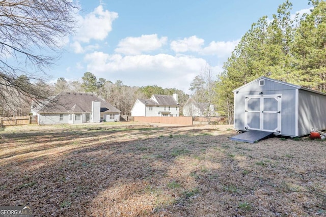 view of yard with a storage shed, an outdoor structure, and fence