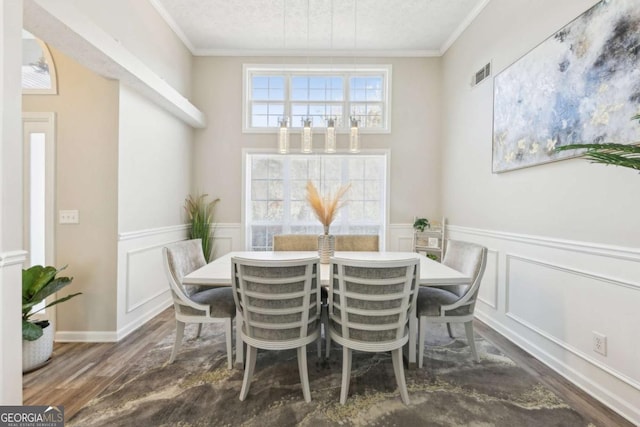 dining space with crown molding, wood finished floors, visible vents, and wainscoting