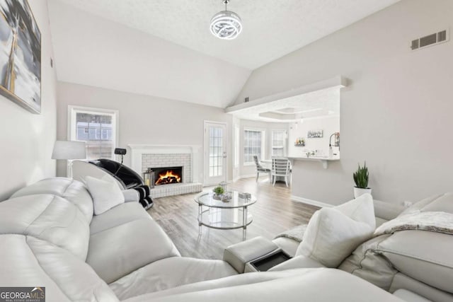 living area featuring visible vents, plenty of natural light, lofted ceiling, and wood finished floors