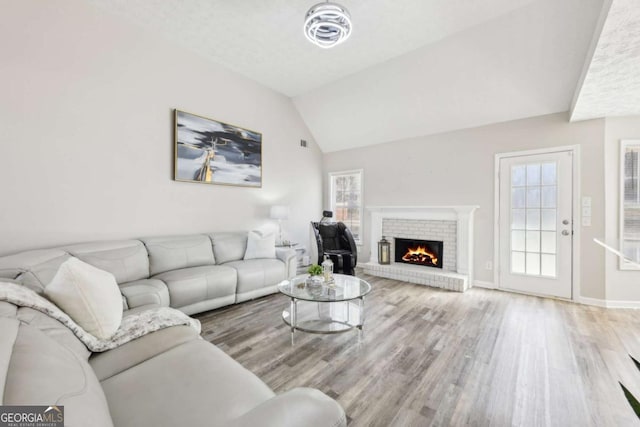 living room with lofted ceiling, wood finished floors, a fireplace, and baseboards