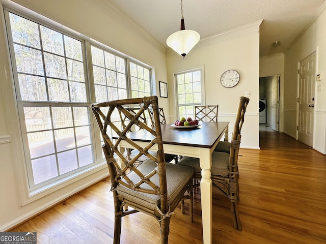 dining area featuring washer / clothes dryer, wood finished floors, baseboards, and ornamental molding