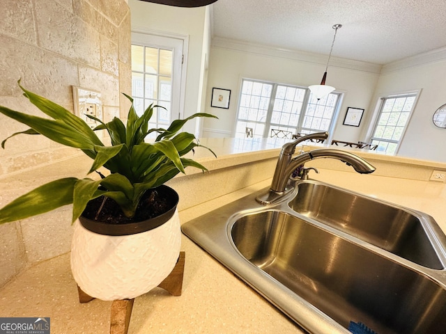 room details with a sink, a textured ceiling, pendant lighting, and crown molding