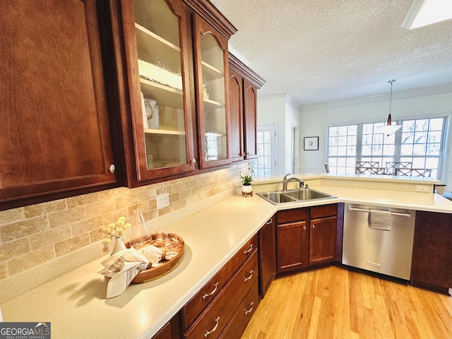 kitchen featuring glass insert cabinets, dishwasher, light wood-style flooring, a peninsula, and a sink