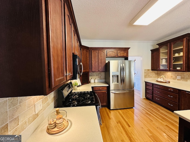 kitchen with tasteful backsplash, stainless steel appliances, light wood-style floors, light countertops, and glass insert cabinets