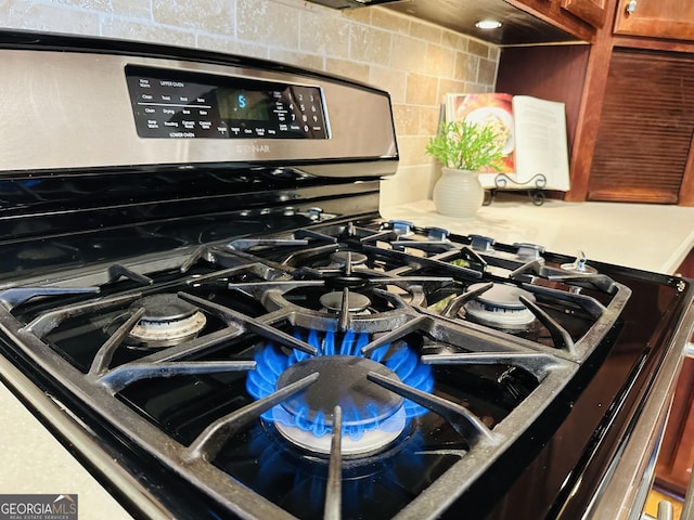 details featuring tasteful backsplash and gas stove