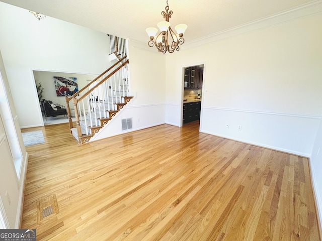 unfurnished room featuring a notable chandelier, stairway, light wood-type flooring, and visible vents