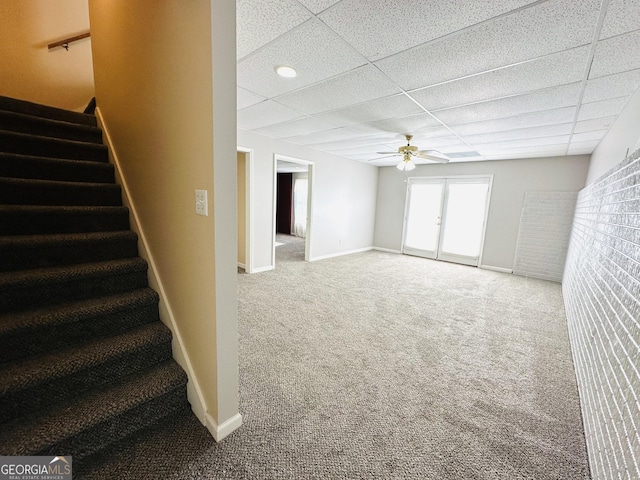 interior space with ceiling fan, a paneled ceiling, baseboards, and carpet floors