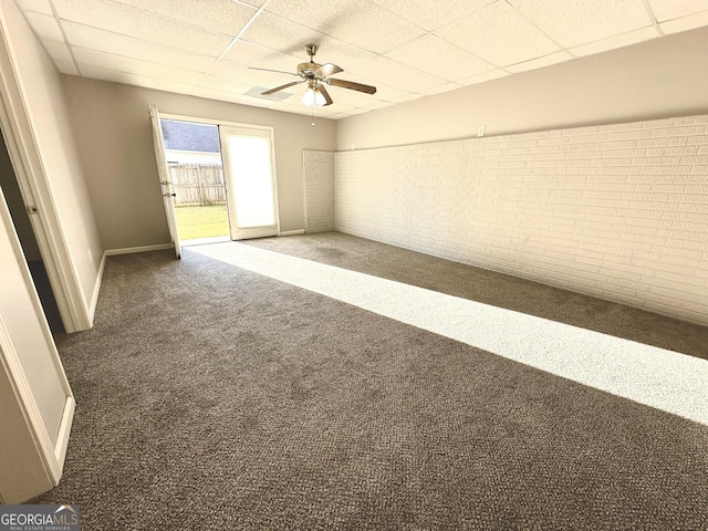 empty room with carpet flooring, baseboards, ceiling fan, and a drop ceiling