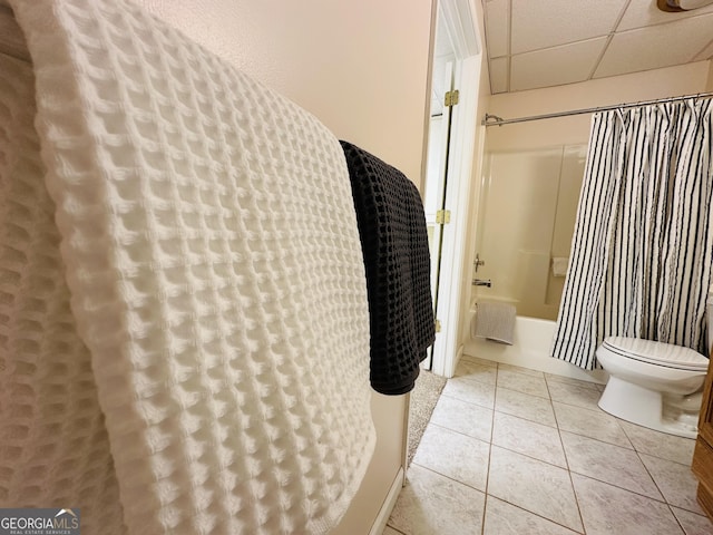 bathroom with tile patterned flooring, a drop ceiling, toilet, and shower / bathtub combination with curtain