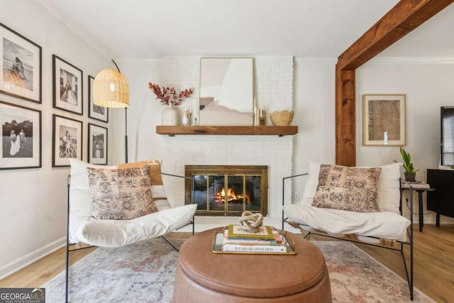 living area with a brick fireplace, crown molding, and wood finished floors