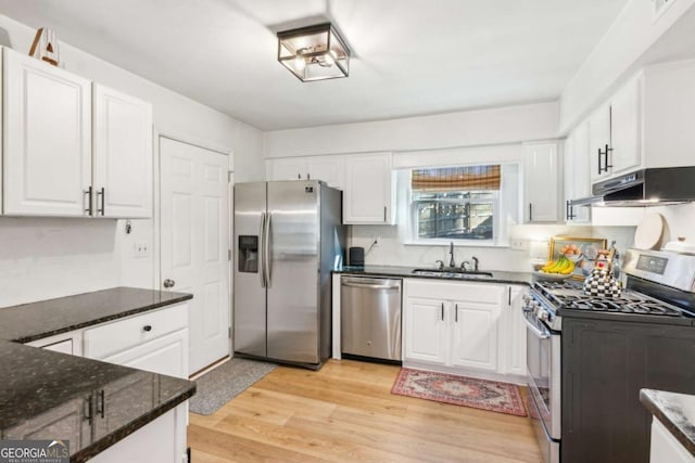 kitchen with light wood-style flooring, under cabinet range hood, a sink, stainless steel appliances, and white cabinets