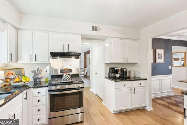 kitchen with visible vents, light wood-style floors, under cabinet range hood, white cabinetry, and stainless steel gas stove