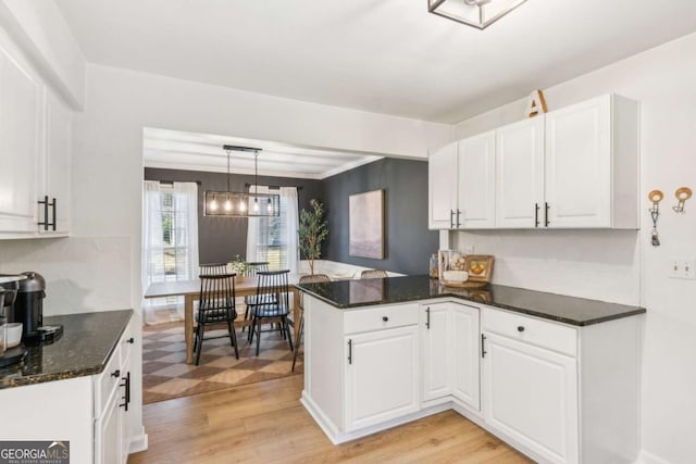 kitchen with a peninsula, white cabinets, and light wood finished floors