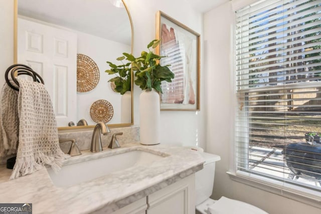 bathroom featuring a wealth of natural light, toilet, and vanity