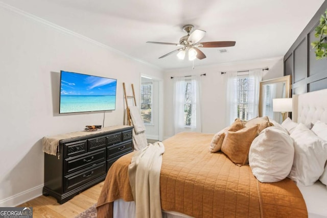 bedroom featuring a ceiling fan, crown molding, light wood-style floors, and baseboards