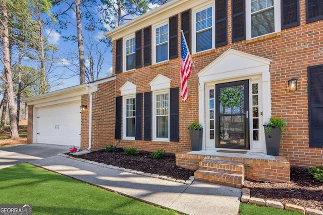 doorway to property with brick siding, driveway, and an attached garage