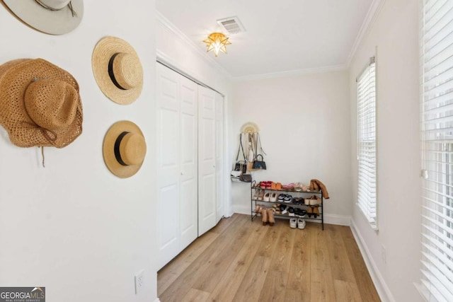 interior space featuring crown molding, light wood-style floors, visible vents, and baseboards