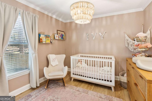 bedroom with a crib, wood finished floors, and ornamental molding