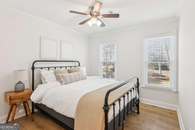 bedroom with light wood finished floors, crown molding, and baseboards