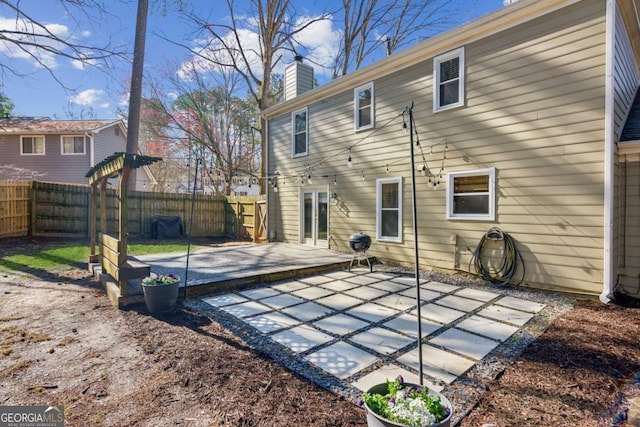 back of house with a patio area, a chimney, and fence