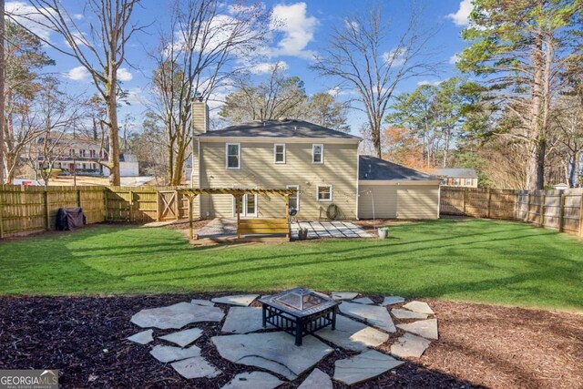 back of property featuring a fire pit, a chimney, a fenced backyard, and a lawn