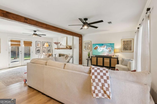 living room with wood finished floors, visible vents, a fireplace, french doors, and beamed ceiling