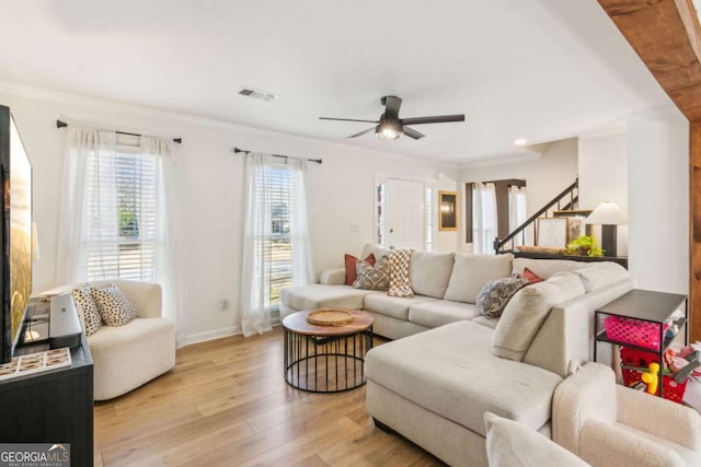 living area featuring visible vents, baseboards, ceiling fan, ornamental molding, and light wood-style flooring