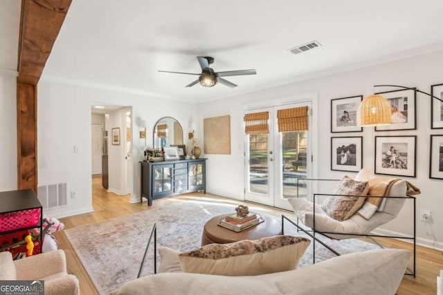 living room with ceiling fan, visible vents, baseboards, and wood finished floors