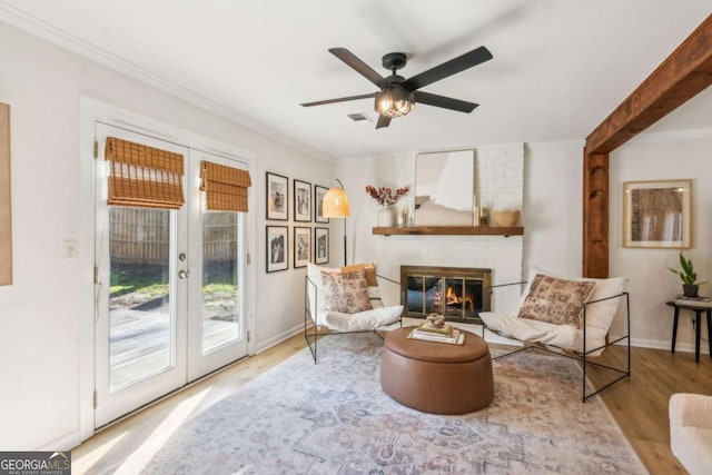 living area featuring visible vents, wood finished floors, french doors, crown molding, and a brick fireplace