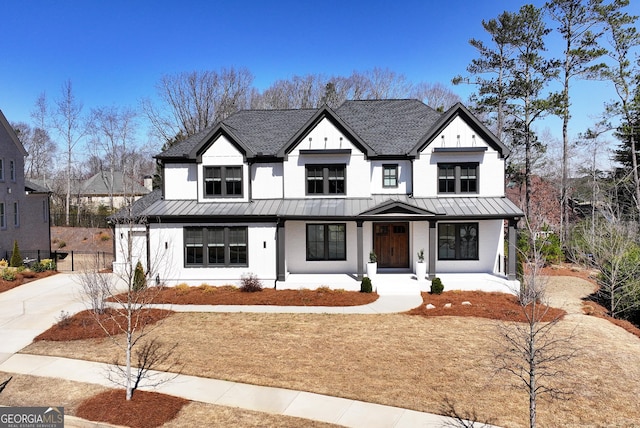 modern farmhouse featuring driveway, a standing seam roof, covered porch, a shingled roof, and metal roof